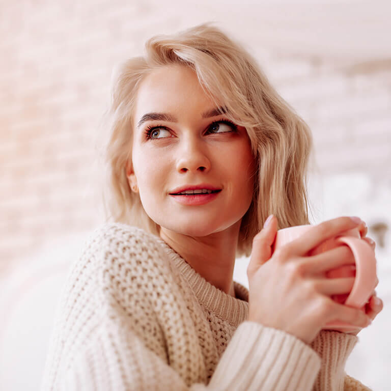 Frau mit chronischer Blasenentzündung wärmt sich an einer Tasse Tee.